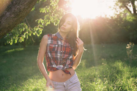Attractive young woman enjoying her time outside in park with sunset in background.の写真素材