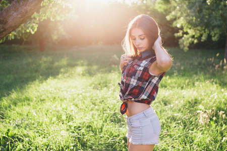 Attractive young woman enjoying her time outside in park with sunset in background.の写真素材