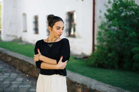 Young beautiful woman walking through the streets of the old town. Woman travels in a beautiful dress. An authentic portrait of young womanの写真素材