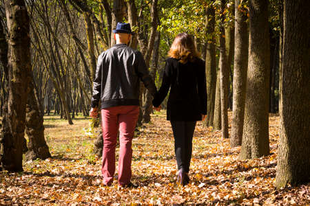 young couple holding hands walking on a parkの写真素材