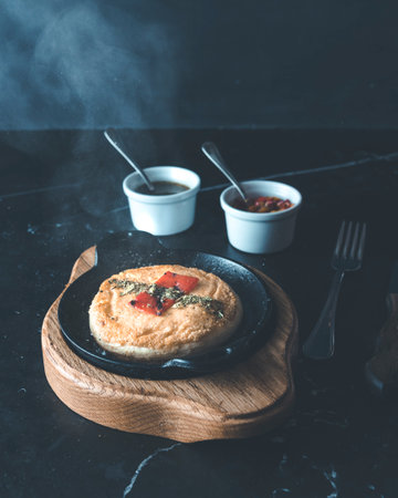Provolone cheese with red peppr in a black plate on a black background