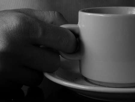 Coffee cup held by a hand, black and white, light and shadowの写真素材