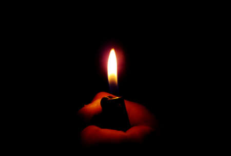 Flame of a lighter in the dark, light and shadow の写真素材