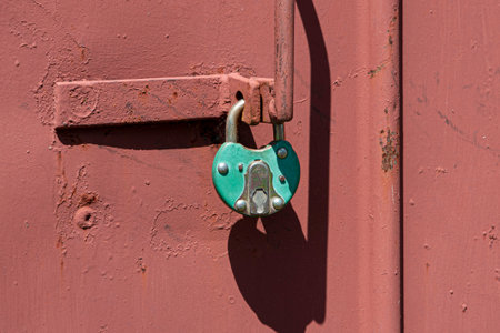 Old rusted grungy metal garage door with latch and padlock. Close up of rusty vintage lock on closed doorの写真素材