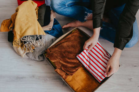 Woman folding and packing clothes into cardboard donation box. Concept of volunteering work, donation and clothes recycling. Helping poor peopleの写真素材