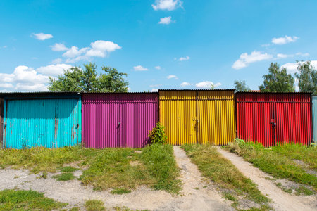 Row of rusty garages or outdoor storage sheds. Old garage door closed with latch, padlock or hasp. Pattern of colorful doorの写真素材