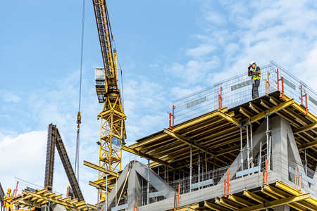 Warsaw, Poland, Sept 2020: Modern building under construction with scaffolding and cranes. Workers in uniforms on construction siteのeditorial素材
