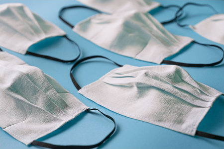 Homemade face protective masks on blue flat lay background. Reusable fabric face masks against virus or flu. Pattern of medical maskの写真素材