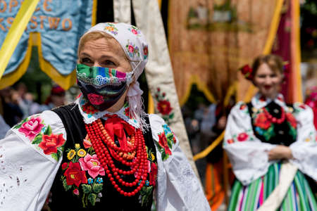Lowicz, June 11, 2020: Portrait of a woman dressed in polish national folk costume from Lowicz region and face protective mask during Corpus Christi processionのeditorial素材