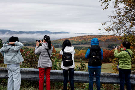 Canada, Quebec, Oct 2018: Asian women tourists admiring scenic view of canadian autumn forest hills...