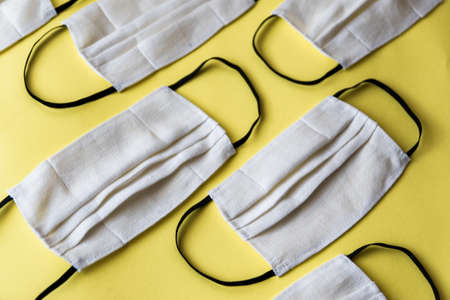 Handmade face protective masks on yellow flat lay background. Reusable face masks against virus  or flu. Pattern of medical maskの写真素材