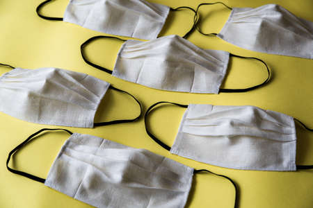 Handmade face protective masks on yellow flat lay background. Reusable face masks against virus or...