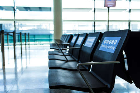 Empty priority seats at an airport in the waiting area. Blue signs on chairsの写真素材