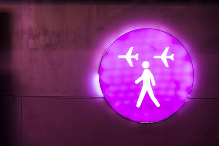 Purple sign with neon light at an international airport. Flight connections sign. Traveling by planeの写真素材