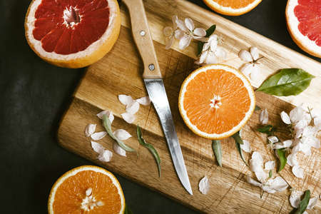 Juicy oranges and grapefruit cut in halves on wooden board on flat lay background. Preparing detox citrus juice rich in vitamin cの写真素材