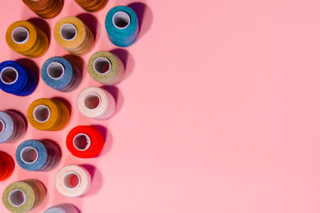 Top view of sewing accessories, sewing threads on pink background