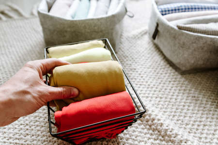 Organizing clothes, folding laundry in baskets and boxes in bedroomの写真素材