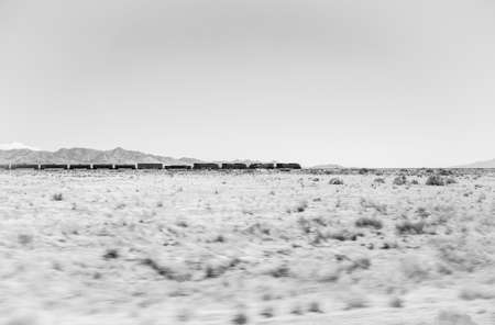 Long train with many wagons crosses California passing through the desertの写真素材