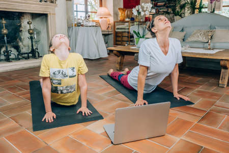 Mother and daughter practicing online yoga classes at home during the quarantine during the...