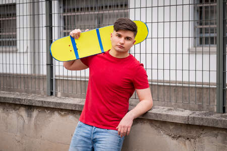 Teen Boy is sitting resting with Longboard - Young adults outdoor skating - A young guy with a...