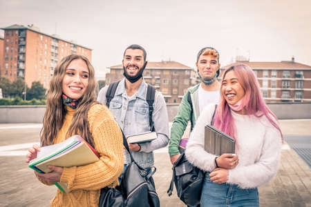 Education, healthcare and pandemic concept - Group of universitary students wearing face protective medical masks for protection from virus disease with backpacks walking and talking outdoorsの写真素材