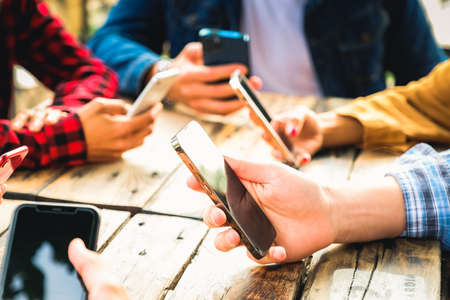 Group of friends checking social media on smartphones at restaurant or pub and ignoring each other - Close up of hands texting - Leisure, technology and people conceptの写真素材