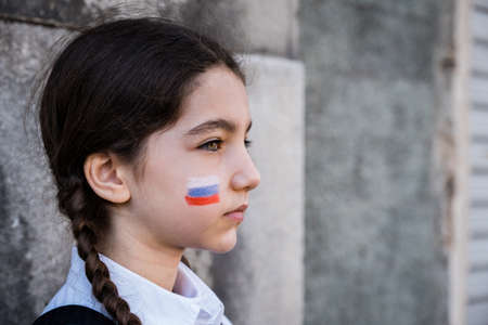 Portrait of a sad child girl with Russian colors on face. Peace and protection children conceptの写真素材