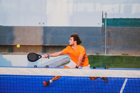 Padel match in a blue grass padel court - Handsome boy player playing a matchの写真素材
