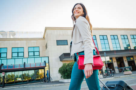 Portrait of a business woman commuter walking in a train station or airport going to boarding gate with hand luggageの写真素材