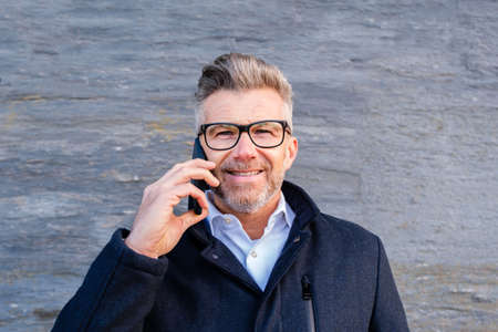 Portrait of businessman in glasses speaking on smartphone