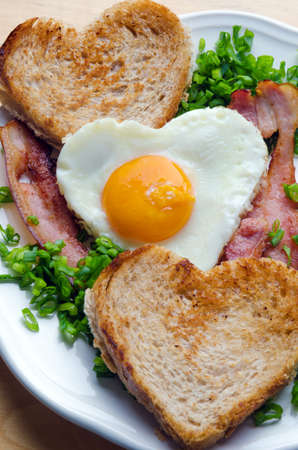 Fried egg in the shape of a heart with bacon and toast.の写真素材