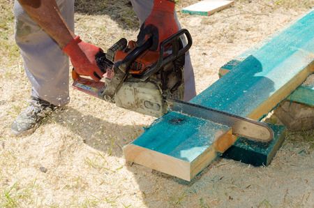 Man sawing a wooden beam with a chain sawの写真素材