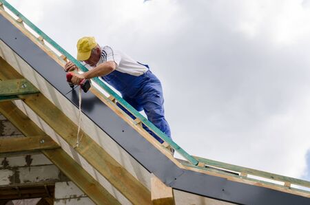A worker standing on the scaffolding and finishing a roofの写真素材
