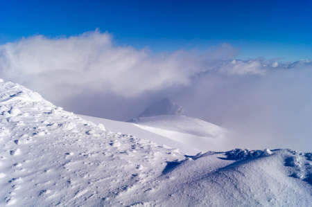 snow in the mountains, fog in the distance, blue sky