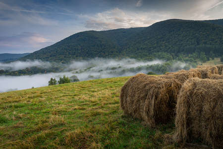Bieszczady, mountains in the fog, autumn season, straw bale. In the distance a forest covered with fogの写真素材