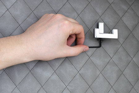 A locksmith installs a clothes hook on a decorative wall of genuine leather. Close-upの写真素材