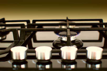 A gas cooker with regulators on a black yellow background. The burner is lit. Selective focusの写真素材