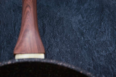 A frying pan with a wooden handle on a ceramic chair. Close-up. Selective focus on the table. Copy Spaceの写真素材