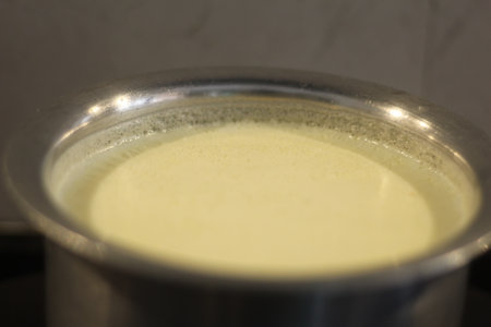 Creamy milk in a pot on a stove, close-upの写真素材