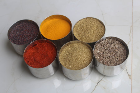 Variety of spices in metal measuring spoons on white marble background. Authentic Indian Spices are used in all the kitchens in India.の写真素材