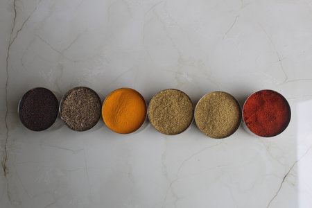 Top view of different types of spices in bowls on white marble background, Authentic Indian Spices are used in all the kitchens in India.の写真素材
