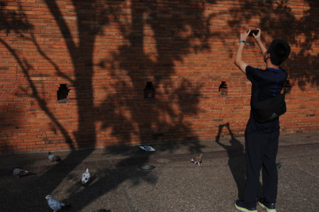 An Asian  young man taking photo of ancient wall Tha Pae Gate. It is one of the most popular tourist attraction in Chiang Mai, Thailand.のeditorial素材