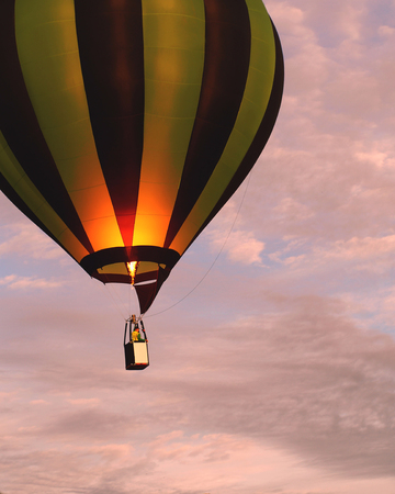 Hot air balloon rising with burner flame and passengers in basketの写真素材