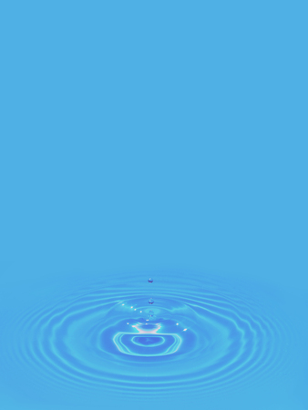 Water Droplets Splashing and Dripping on a Smooth Blue Surface creating a Ripple Effectの写真素材
