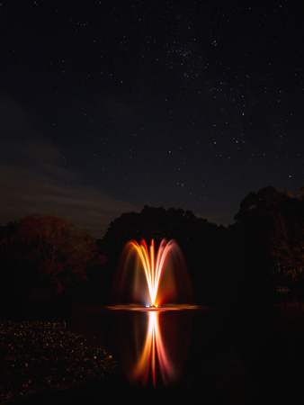 Colorful Spotlights Light up a Water Fountain at Gilmour Lake at Night time Waihi New Zealandの写真素材