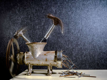 A Grinder crushing Hammers into Nails Creative Conceptの写真素材