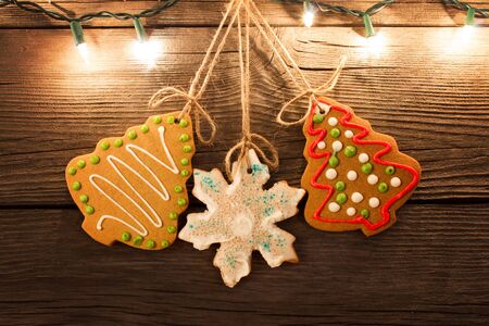 gingerbread cookies hanging with worn wooden background with christmas lights illuminated