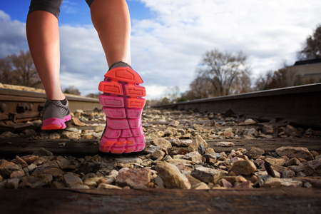 woman running down railroad tracks during the sunlight shallow depth of fieldの写真素材