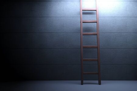 Wooden ladder lit by spotlight on concrete backgroundの写真素材