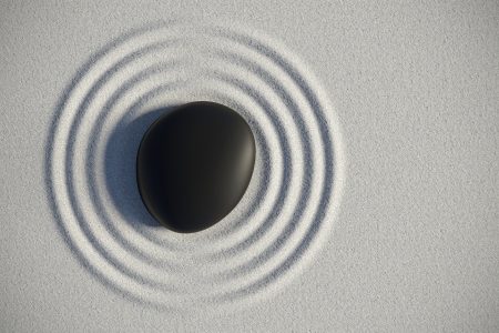 Zen garden on sand with a black stone at the center of an harmony ripplesの写真素材